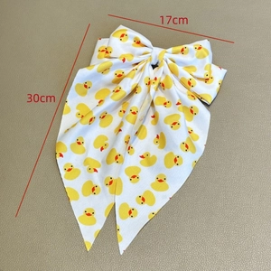 Barrette à cheveux nœud avec canards jaunes, mesure 17cm par 30cm sur tissu blanc