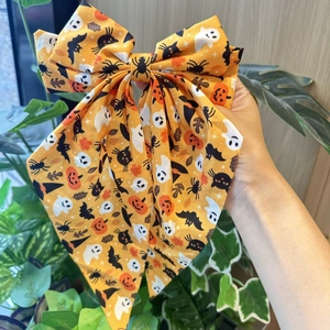 Detail view of large Halloween bow clip with orange pumpkin, ghost and bat print patterns