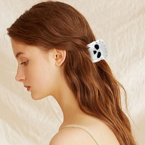 Detail of white skull hair claw clip with diamonds worn on side-view brown hair