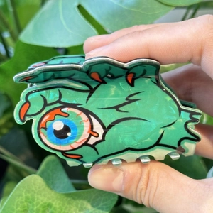 Détail de la pince à cheveux main de monstre verte avec un œil pour fête d'Halloween