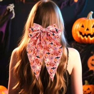 Pink Halloween bow hair clip with bat and ghost prints worn by a model in a dark setting