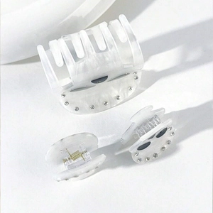 Detail of cream acetate hair claws with sparkling rhinestones and elegant pearl texture