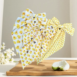 Vue détaillée des barrettes à nœud imprimé canard jaune avec texture de tissu et rubans