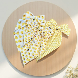 Détail d'un nœud papillon à motif canard jaune avec de longs rubans sur plateau