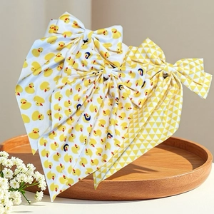 Barrettes à nœuds avec motifs de canard jaune et longs rubans sur plateau en bois