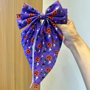Detailed view of Halloween purple satin bow hairpin featuring pumpkin and ghost patterns