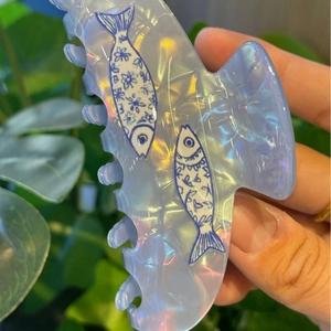 Close-up of blue whale hair claw clip with floral patterns and pearlescent finish