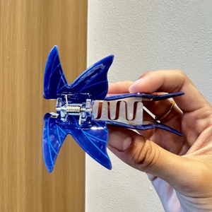 Vue latérale détaillée d'une pince à cheveux papillon bleue avec mécanisme à ressort