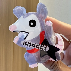 Detail of cartoon opossum hair claw clip playing a guitar with purple marble texture