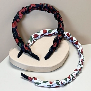 Detailed close-up of cherry print headband with ruched fabric and protective end tips