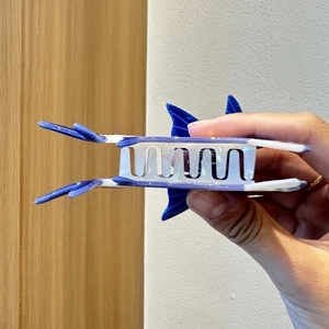 Détail d'une pince à cheveux baleine bleue et blanche en acétate brillant poli