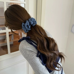 Rear view of a blue polka dot scrunchie styled on a ponytail for a sweet look