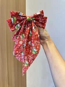 Close-up of a festive red Christmas bow hair clip with snowman and snowflake prints