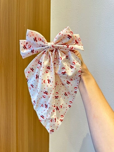 Détail d'un grand nœud de Noël pour cheveux avec motifs Père Noël et étoiles dorées