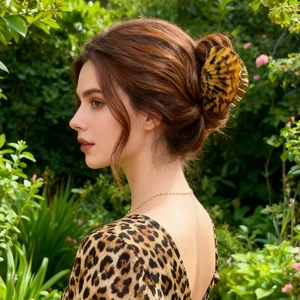 Elegant leopard print hair claw clip shown on a woman with dark hair in a lush garden