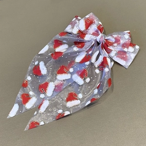 Vue détaillée du nœud de Noël en maille blanche avec motifs de chapeaux de Père Noël rouges