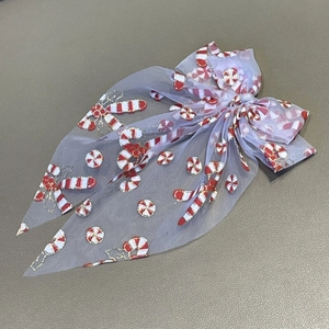 Detailed macro view of purple mesh Christmas bow hair clip with candy cane embroidery