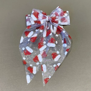Détail du nœud de Noël en maille blanche avec paillettes et motifs de bonnets de Noël