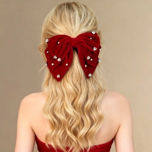 Dettaglio di un fiocco in velluto rosso con strass luccicanti su capelli biondi mossi
