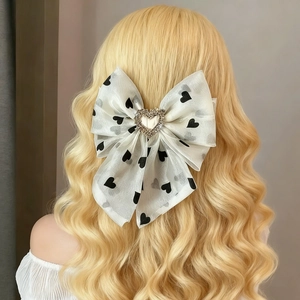 Elegant mesh bow hair clip with black hearts and rhinestone heart center on blonde hair