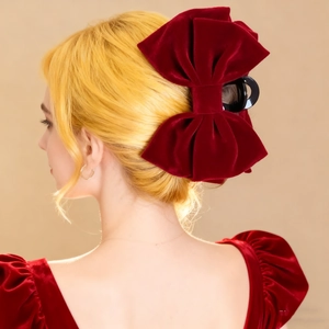 Elegant large red velvet bow hair claw clip styled on a woman's half-up hairstyle