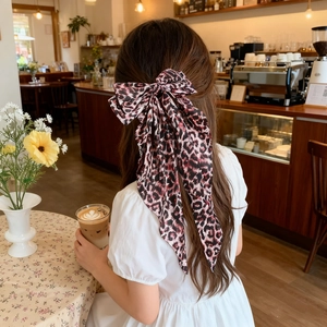 Back view of a large leopard print chiffon bow clip decorating a long hairstyle