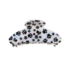 Vue détaillée de la pince à cheveux blanche marbrée avec des motifs de pattes noires