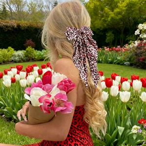 Detailed back view of an oversized leopard print bow hair clip on model in a garden