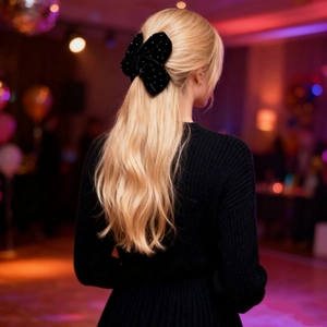 Elegant black velvet hair clip with rhinestone dots worn by model in a festive setting