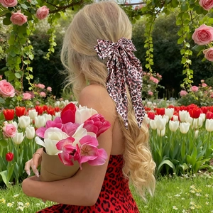 Elegant leopard print bow hair clip with flowing ribbon on blonde wavy hair