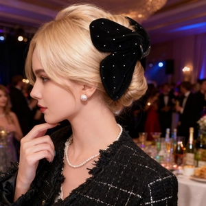 Elegant black velvet bow hair claw clip with white dots on woman wearing tweed jacket