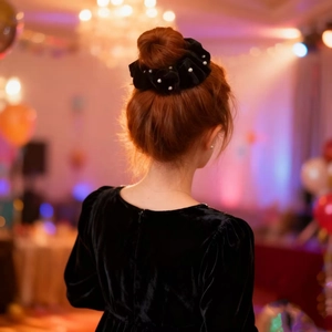 Elegant black velvet scrunchie with white pearls on a low ponytail for formal hairstyle