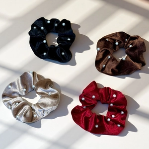 Detail view of velvet scrunchies with white pearls in black, brown, champagne and wine red
