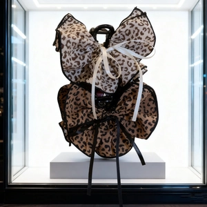 Detail of leopard print double bow hair claws with elegant ribbon edges on white stand