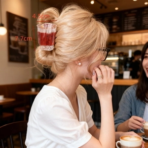 Detailed size view of drink cup hair claw clip on model in a cozy cafe setting