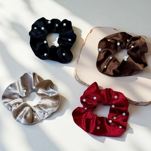 Detail of four velvet pearl hair scrunchies in black, coffee, champagne and burgundy red