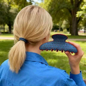 Close-up of denim red polka dot hair claw clip and ponytail tie on a sunny park background