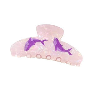 Detail of pink pearlescent ocean-style hair claw with purple whale patterns and shell luster