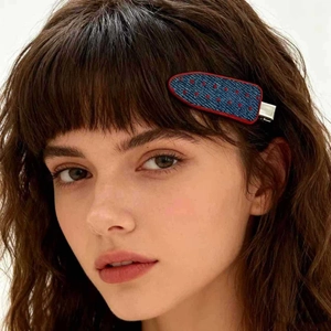 Detail of denim blue shark hair claw with red polka dots on dark wavy hair