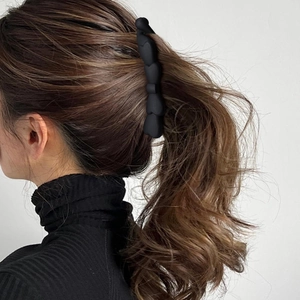 Matte schwarze Haarspange mit Herzmuster, präsentiert an Model mit langen Locken