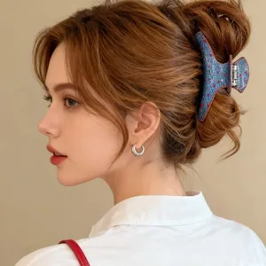 Detail of blue denim hair claw clip with red polka dots worn by a female model