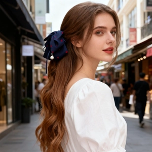 Pince à cheveux noeud bleu à pois rouges avec perle sur cheveux bouclés