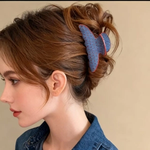 Detail of a large denim hair claw clip with red polka dots worn by a female model