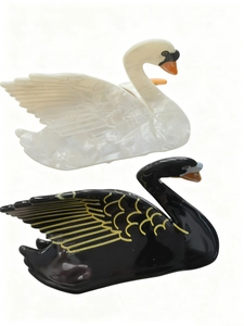 Detailed view of swan-shaped hair claws in pearly white and black acetate material