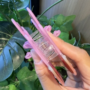 Roze kwal haarklem met hartvormige strass details getoond in een lifestyle handweergave