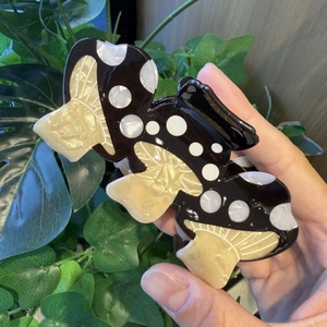 Close-up of mushroom hair claw clip with black white polka dots and pearlescent finish