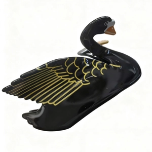 Detail view of the black swan hair claw clip with golden wing textures and glossy finish