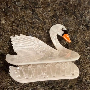 Detailed view of an elegant marble white swan hair claw clip with orange beak on stone background