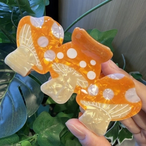 Detail of creative orange and white mushroom hair claw clip with marble texture