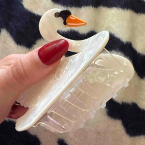 Detailed close-up of a pearl white swan hair claw clip with orange beak and black eye